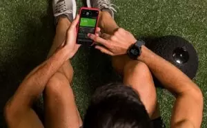 Athlete sat on floor connecting garmin watch to smartphone